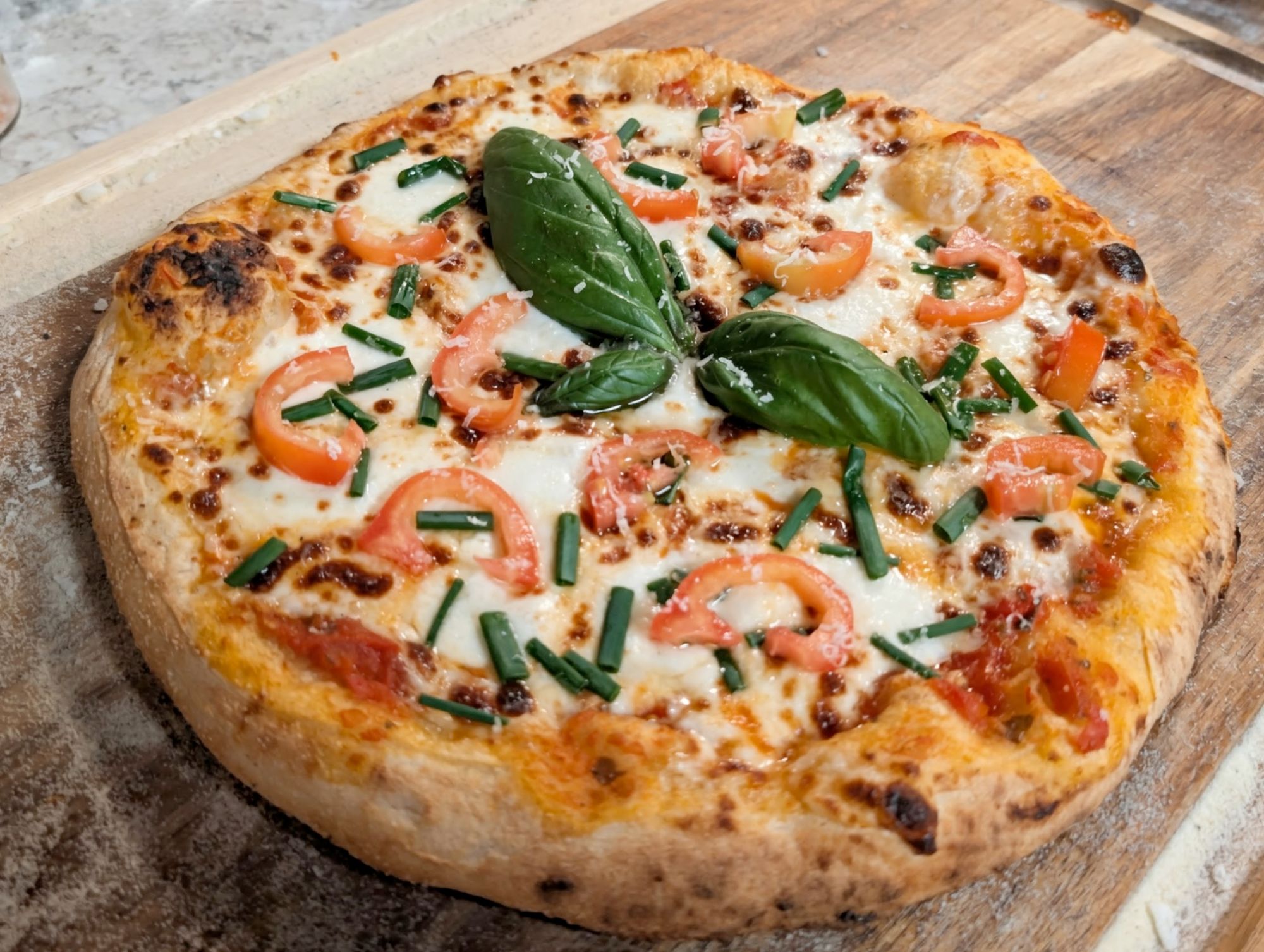 Margherita pizza with fresh basil, tomatoes, mozzarella, and chives