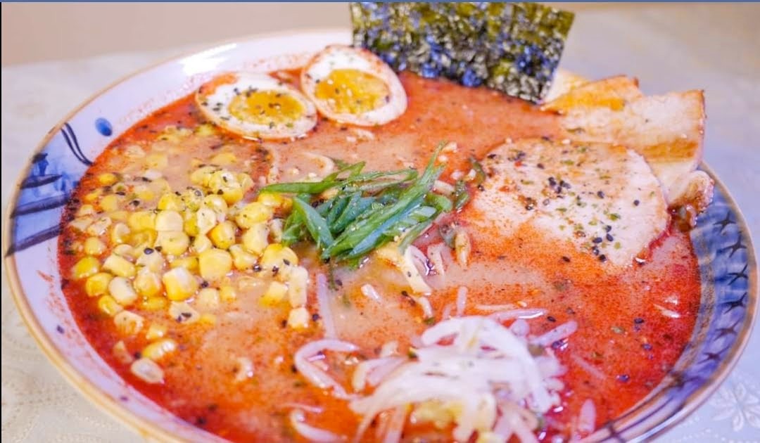 Spicy red broth ramen with chashu, charred corn, nori, and soft-boiled egg